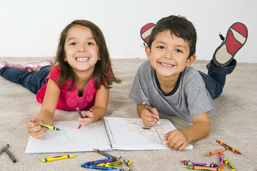 Kids laying down on clean fresh carpet coloring.